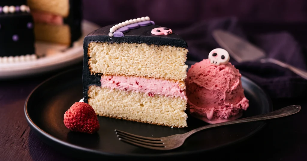 Single slice of kuromi cake showing vanilla sponge layers with pink strawberry buttercream filling, black frosting exterior, and a scoop of strawberry ice cream on a black plate